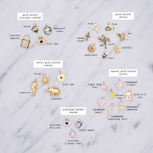 Load image into Gallery viewer, gold plated zirconia charms heart cross padlock evil eye tree fish bee chunky cross cupid sunflower star initial 24k matte daisy seahorse elephant light pink yellow enamel champagne seahorse clover lightning bolt puffy heart platinum plated 8 point star on marble labelled