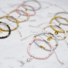 Load image into Gallery viewer, beaded tie up square knot nylon polyester cord grey pink blue cream white olive green metallic antique gold bronze silver tan charm bracelets with tassels friendship bracelets on marble