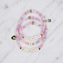 Load image into Gallery viewer, unicorn painted shimmer beads ice cream multicolour 24K gold plated heart charm with zirconia gold star charm happy bunny trio stacked elastic stretch bracelets gold letter beads plastic on marble 
