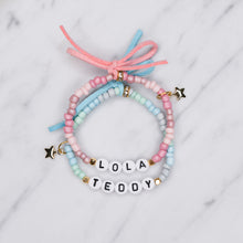 Load image into Gallery viewer, ombre pink blue painted beaded stretch elastic bracelets suede bows colourful gradient pattern gold plated star charms lola teddy girls boys childrens name custom personalised rondelle sparkly plastic beads on marble
