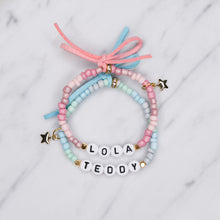 Load image into Gallery viewer, ombre pink blue painted beaded stretch elastic bracelets suede bows colourful gradient pattern gold plated star charms lola teddy girls boys childrens name custom personalised rondelle sparkly plastic beads on marble