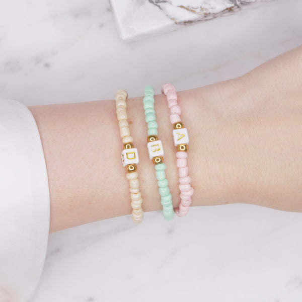 beaded painted pastel pink cream green block cubic initial gold letter colour personalised custom bracelet gold accents 3 bracelets on wrist