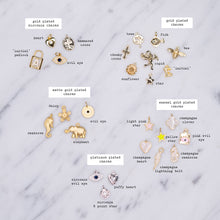Load image into Gallery viewer, gold plated zirconia charms heart cross padlock evil eye tree fish bee chunky cross cupid sunflower star initial 24k matte daisy seahorse elephant light pink yellow enamel champagne seahorse clover lightning bolt puffy heart platinum plated 8 point star on marble labelled

