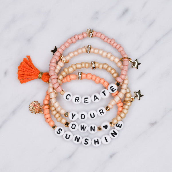 create your own sunshine pink coral orange champagne shimmer painted beaded bracelets gold plated stars charms sunflower orange tassel affirmation bracelets stack colourful on marble