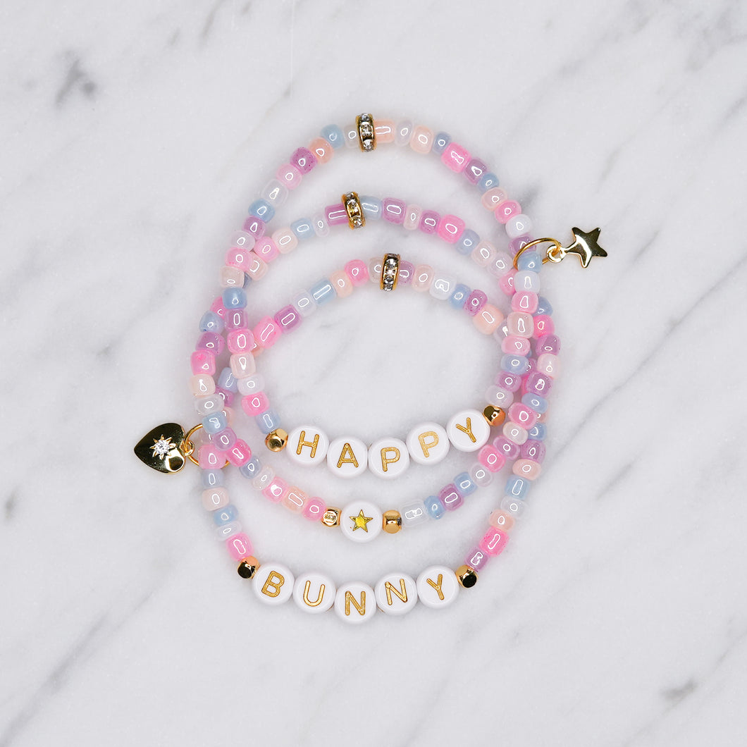 unicorn painted shimmer beads ice cream multicolour 24K gold plated heart charm with zirconia gold star charm happy bunny trio stacked elastic stretch bracelets gold letter beads plastic on marble 