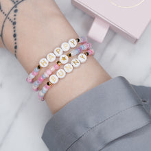 Load image into Gallery viewer, unicorn painted shimmer beads ice cream multicolour 24K gold plated heart charm with zirconia gold star charm happy bunny trio stacked elastic stretch bracelets gold letter beads plastic on wrist with grey shirt

